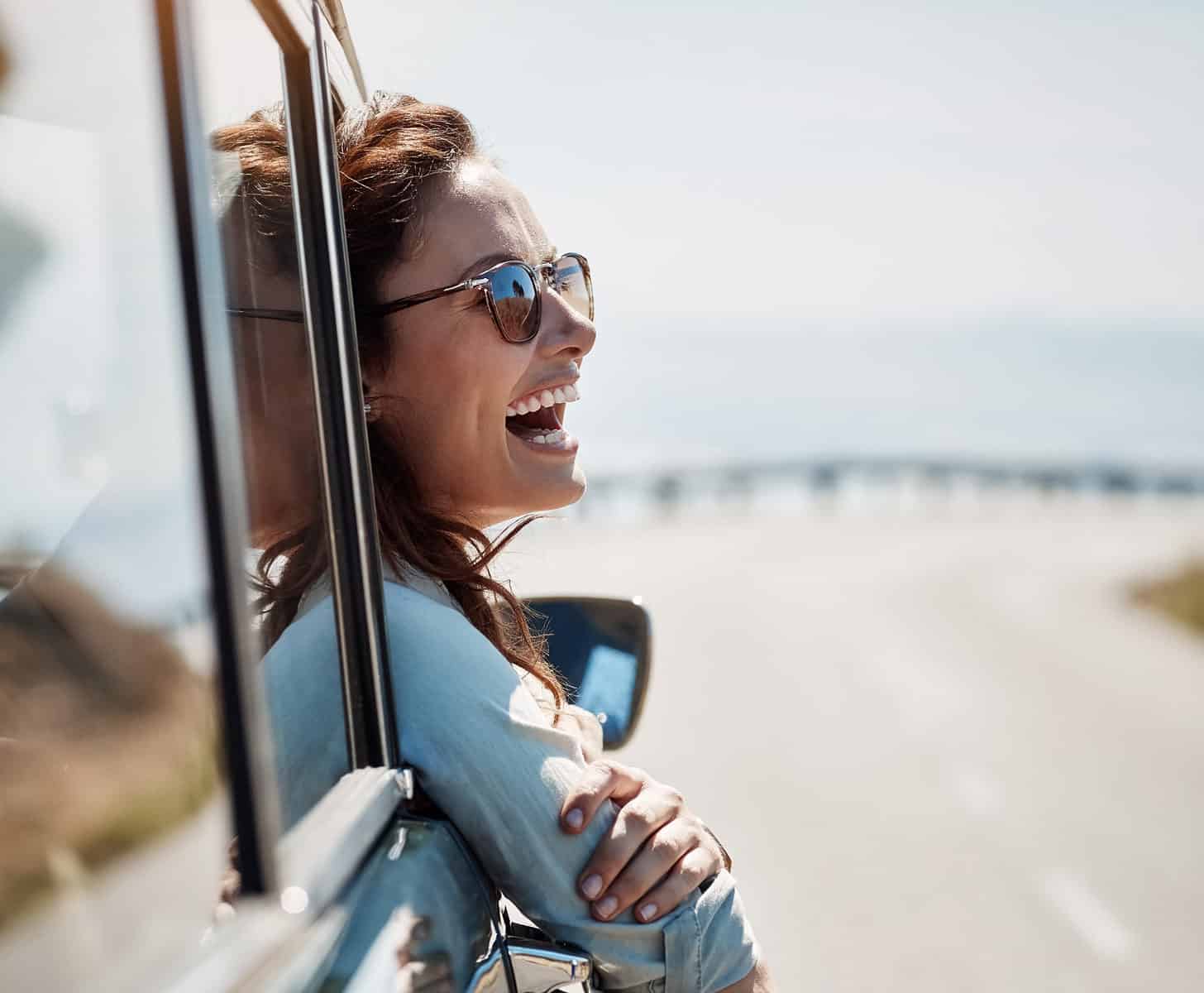 woman-laughing-with-head-out-car-window